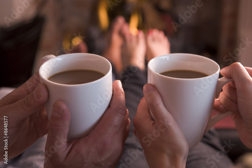 Photo: Feet warming at fireplace with hands holding coffee Feet warming at fireplace with hands holding coffee