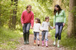 Family walking on path holding hands smiling