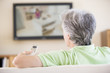 Photo: Man watching television using remote control Man watching television using remote control