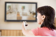 Photo: Woman watching television using remote control Woman watching television using remote control