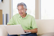Photo: Man in living room with laptop smiling Man in living room with laptop smiling