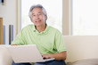 Photo: Man in living room with laptop smiling Man in living room with laptop smiling