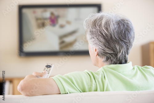 Photo: Man watching television using remote control Man watching television using remote control