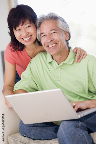 Photo: Couple in living room with laptop smiling Couple in living room with laptop smiling