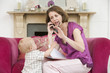 Photo: Mother using telephone in living room with baby frowning Mother using telephone in living room with baby frowning