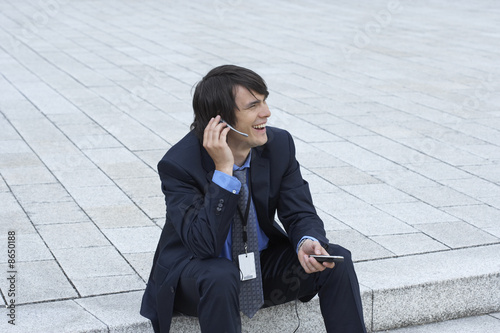  Mobile Headset on Businessman Sitting On Steps With Headset And Mobile Talking Looking