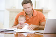 Photo: Father and baby in dining room with laptop Father and baby in dining room with laptop