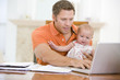 Photo: Father and baby in dining room with laptop Father and baby in dining room with laptop
