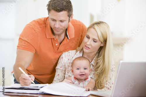 Photo: Couple and baby in dining room with laptop Couple and baby in dining room with laptop