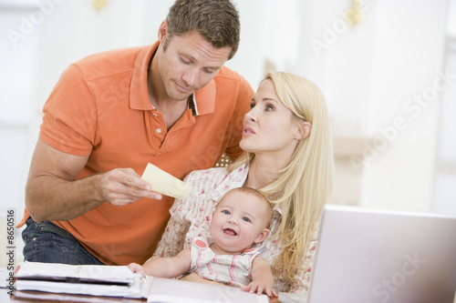 Photo: Couple and baby in dining room with laptop and paperwork Couple and baby in dining room with laptop and paperwork
