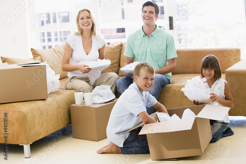 Photo: Family unpacking boxes in new home smiling Family unpacking boxes in new home smiling