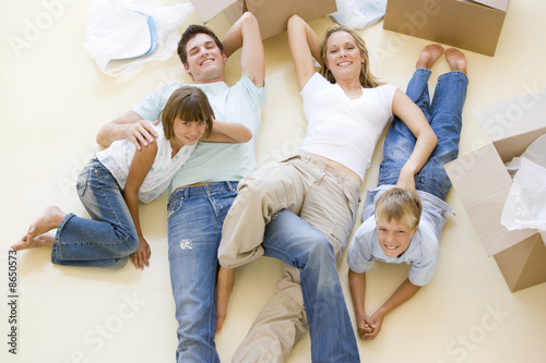 Photo: Family lying on floor by open boxes in new home smiling Family lying on floor by open boxes in new home smiling