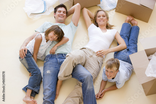 Photo: Family lying on floor by open boxes in new home smiling Family lying on floor by open boxes in new home smiling
