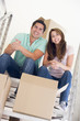 Couple sitting on staircase with boxes in new home smiling
