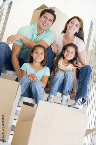 Photo: Family sitting on staircase with boxes in new home smiling Family sitting on staircase with boxes in new home smiling
