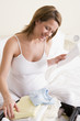 Photo: Pregnant woman packing baby clothing in suitcase holding list sm Pregnant woman packing baby clothing in suitcase holding list sm