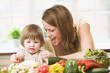 Mother and daughter in kitchen making a salad smiling