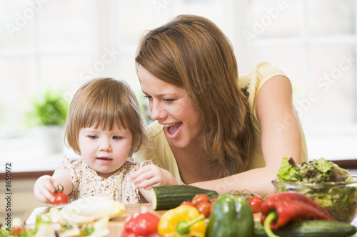 Photo: Mother and daughter in kitchen making a salad smiling Mother and daughter in kitchen making a salad smiling