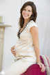 Pregnant woman sitting in living room smiling