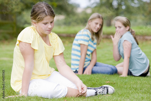 Foto: Two young girls bullying other young girl outdoors Two young girls bullying other young girl outdoors