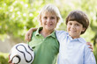 Two young boys outdoors with soccer ball smiling Two young boys outdoors with soccer ball smiling