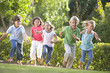 Five young friends running outdoors smiling Five young friends running outdoors smiling