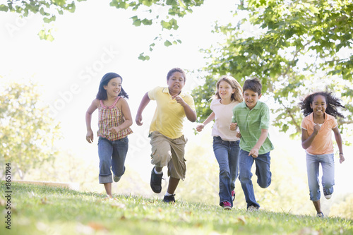 Photo: Five young friends running outdoors smiling Five young friends running outdoors smiling