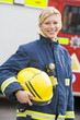 Portrait of a firefighter standing in front of a fire engine
