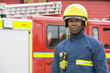 Portrait of a firefighter standing in front of a fire engine