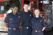Portrait of firefighters standing by a fire engine