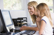 Woman and young girl in home office with computer smiling