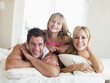 Photo: Family lying in bed smiling Family lying in bed smiling