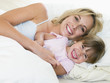 Photo: Woman and young girl in bed smiling Woman and young girl in bed smiling