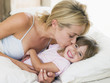 Photo: Woman kissing young girl in bed smiling Woman kissing young girl in bed smiling