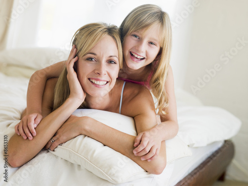 Foto: Woman and young girl lying in bed smiling Woman and young girl lying in bed smiling