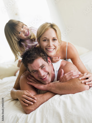 Photo: Family in bed playing and smiling Family in bed playing and smiling