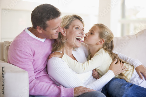 Photo: Family in living room with young girl kissing woman Family in living room with young girl kissing woman