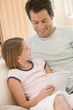 Man and young girl in living room reading book and smiling