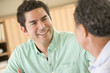 Photo: Two men sitting in living room talking and smiling Two men sitting in living room talking and smiling
