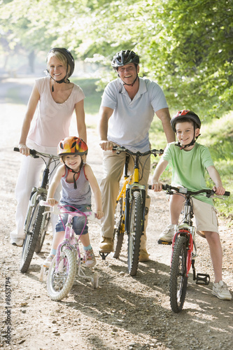 Photo: Family sitting on bikes on path smiling Family sitting on bikes on path smiling