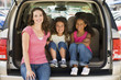 Photo: Woman with two young girls sitting in back of van smiling Woman with two young girls sitting in back of van smiling