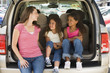 Photo: Woman with two young girls sitting in back of van smiling Woman with two young girls sitting in back of van smiling