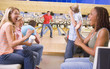 Family in bowling alley with two friends cheering and smiling