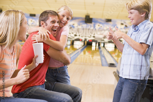 Foto: Family in bowling alley cheering and smiling Family in bowling alley cheering and smiling