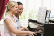Couple playing piano and smiling Couple playing piano and smiling