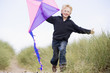 Photo: Young boy running on beach with kite smiling Young boy running on beach with kite smiling