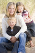 Mother and two young children sitting on beach smiling
