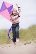 Photo: Young girl on beach with kite smiling Young girl on beach with kite smiling