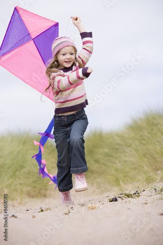 Young girl on beach with kite smiling