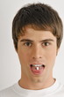 Young male adult with pill on tongue